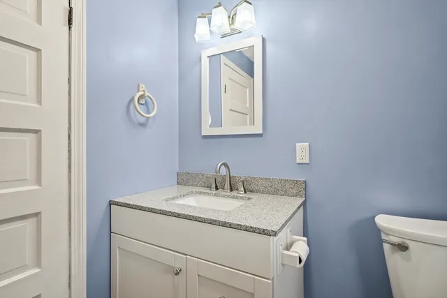 a bathroom with a granite countertop sink a toilet and mirror