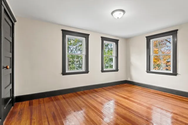a view of an empty room with window and wooden floor