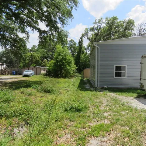 a backyard of a house with plants and large tree