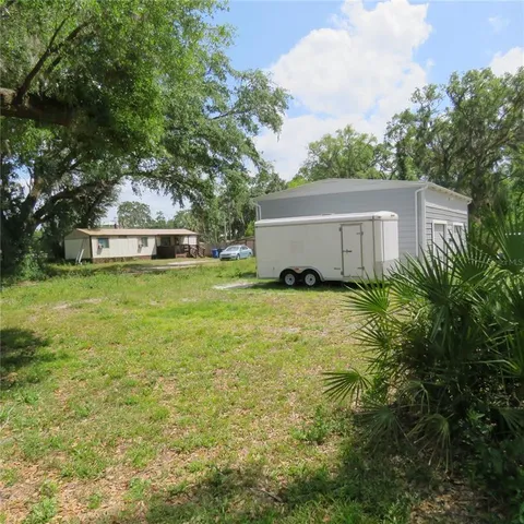 a view of a house with a yard and a large tree