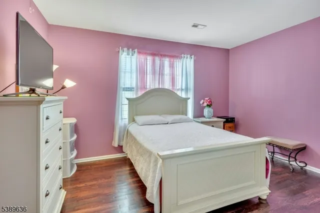 a bedroom with a bed and a flat tv screen on dresser