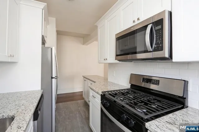 a kitchen with stainless steel appliances granite countertop white cabinets and black stove top oven with granite countertops