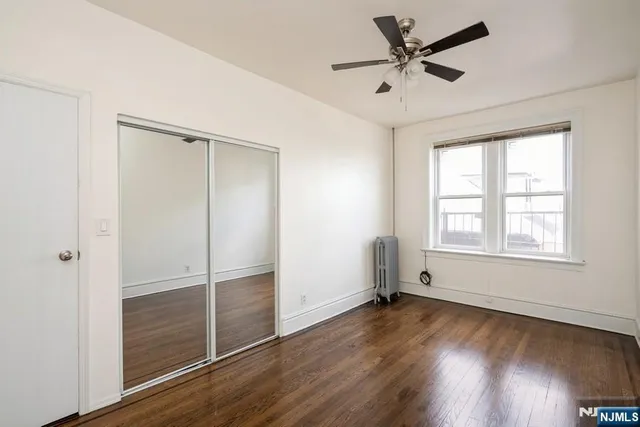 a view of empty room with wooden floor and ceiling fan