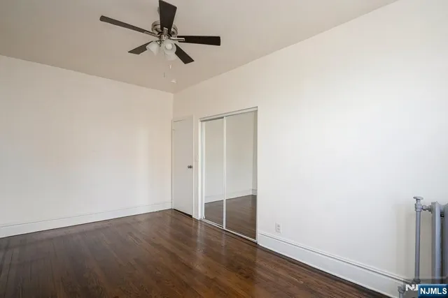 an empty room with wooden floor and fan
