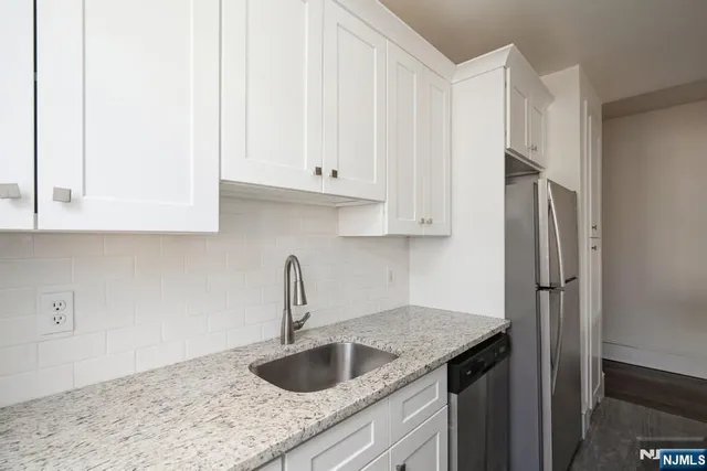 a kitchen with granite countertop a sink stainless steel appliances and cabinets