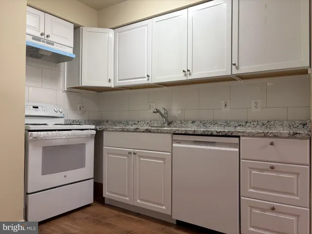 a kitchen with granite countertop white cabinets and white appliances