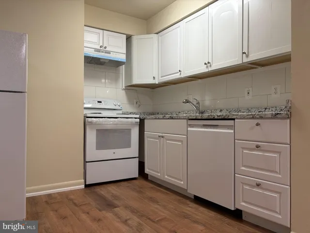 a kitchen with granite countertop white cabinets and white appliances