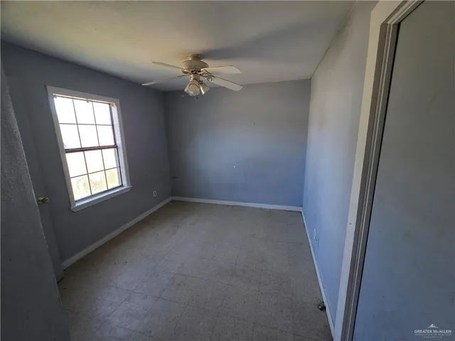 an empty room with windows and fan