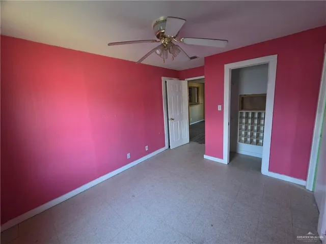 an empty room with a ceiling fan and window