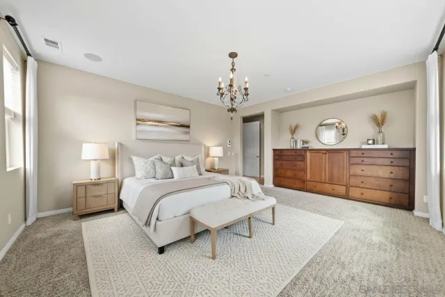 a spacious bedroom with a bed a dresser and mirror