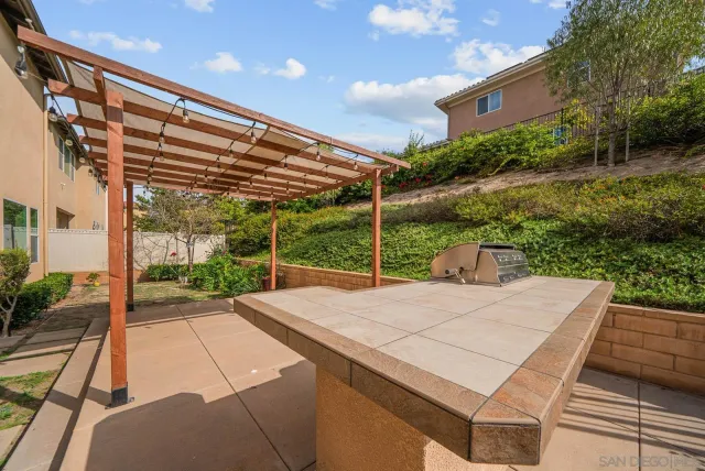 a view of a patio with a table and chairs under an umbrella with a small yard