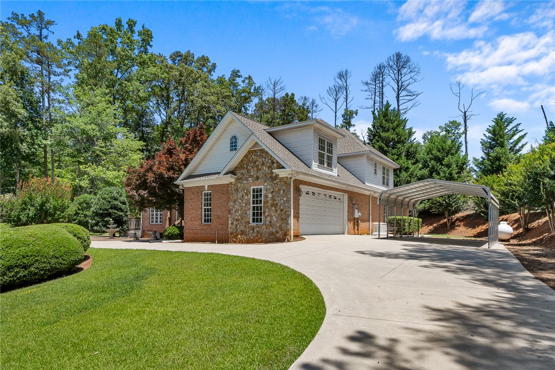 135 Sunset Bay Boulevard Seneca, SC 29672 - Photo 3 of 50 A grand exterior presents a stone and brick facade, a spacious driveway, and an attached garage with an additional carport.