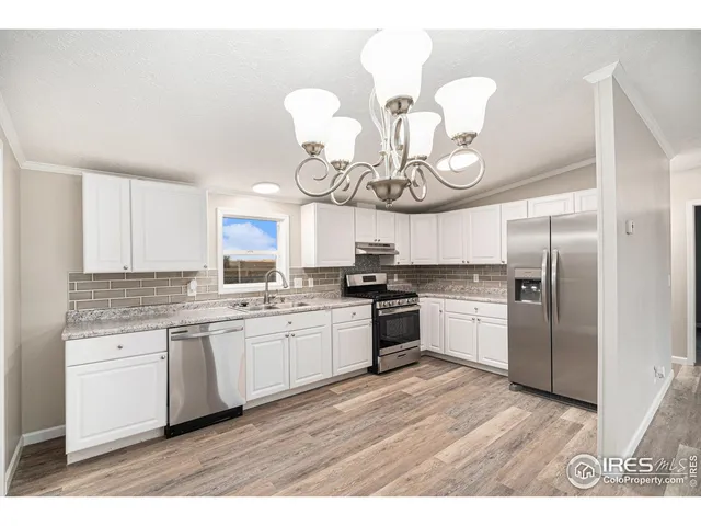 a kitchen with kitchen island granite countertop stainless steel appliances a white cabinets a sink dishwasher a stove and a dining table with wooden floor