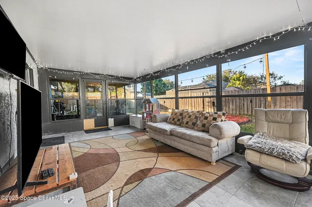 a living room with furniture a flat screen tv and a floor to ceiling window