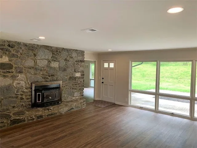 an empty room with wooden floor fireplace and windows