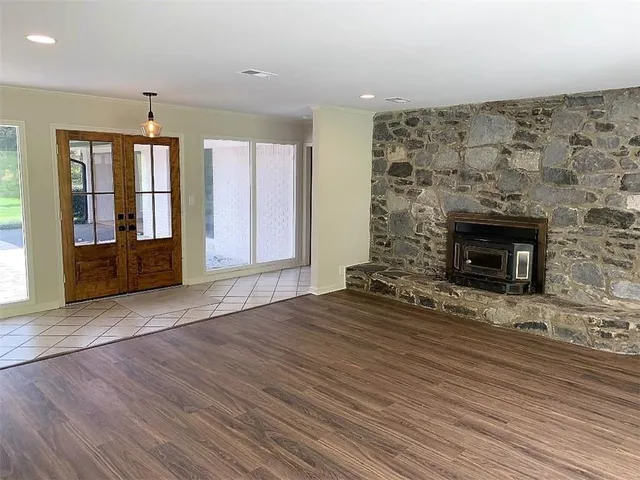 an empty room with wooden floor fireplace and windows