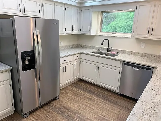 a kitchen with stainless steel appliances white cabinets a sink and a refrigerator