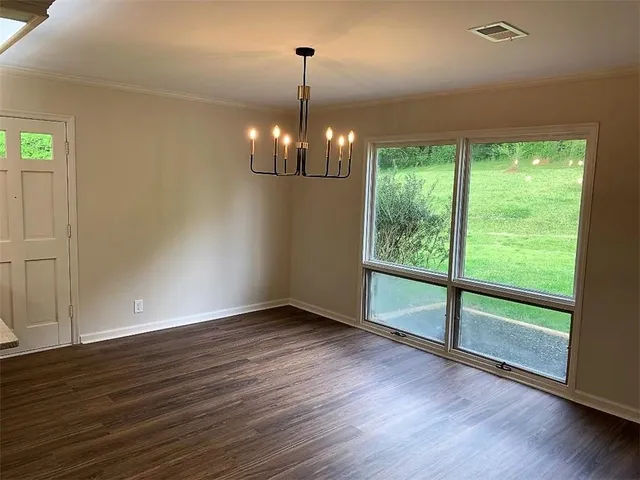 a view of a room with wooden floor chandeliers and kitchen view