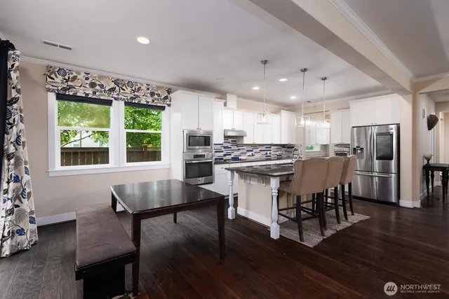 a kitchen with stainless steel appliances kitchen island granite countertop a stove a refrigerator a kitchen island with a dining table and chairs