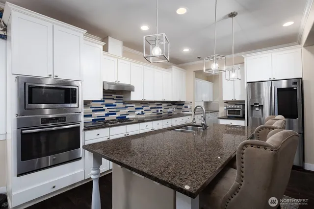 a kitchen with stainless steel appliances granite countertop a stove refrigerator and microwave