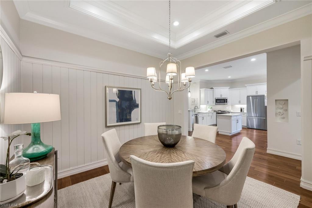 6573 Roma Way Naples, FL 34113 - Photo 16 of 49 Dining room with an inviting chandelier, crown molding, dark wood-type flooring, and a raised ceiling