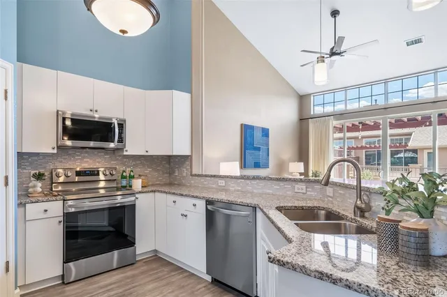a kitchen with granite countertop a stove a sink and a microwave
