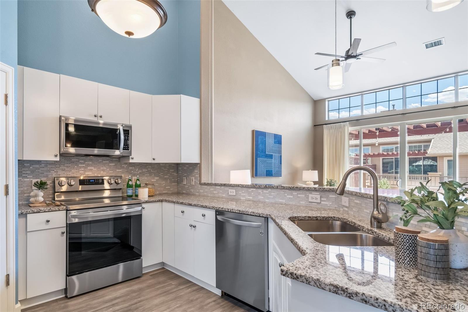 8626 Gold Peak Drive, Unit B Highlands Ranch, CO 80130 - Photo 11 of 40 a kitchen with granite countertop a stove a sink and a microwave