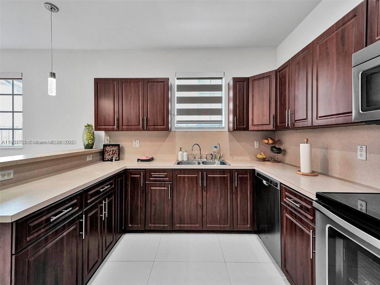 7565 Northwest 177th Terrace, Unit 7565 Hialeah, FL 33015 - Photo 14 of 35 a kitchen with a sink stove top oven and cabinets