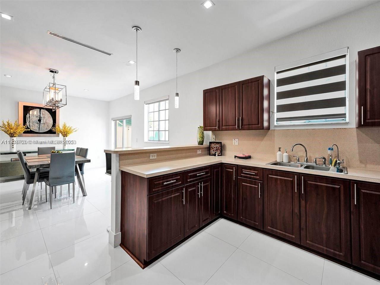 7565 Northwest 177th Terrace, Unit 7565 Hialeah, FL 33015 - Photo 15 of 35 a kitchen with stainless steel appliances granite countertop a stove a sink dishwasher and a microwave oven with cabinets