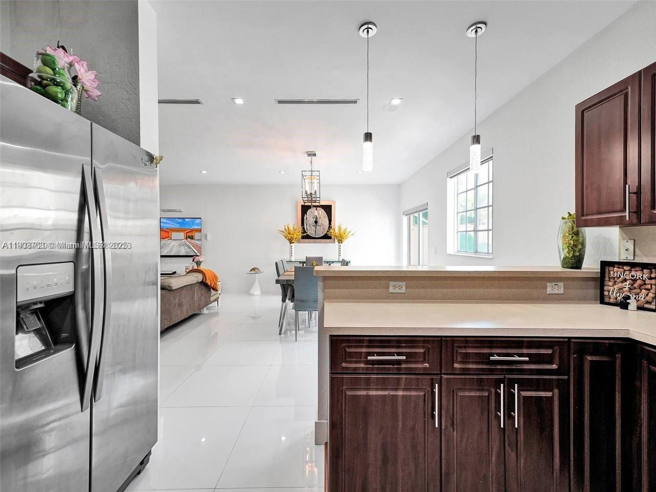 7565 Northwest 177th Terrace, Unit 7565 Hialeah, FL 33015 - Photo 16 of 35 a kitchen with stainless steel appliances granite countertop a sink a stove and a refrigerator