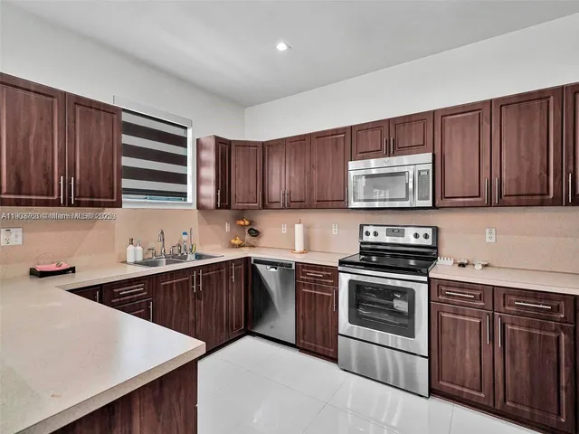 a kitchen with stainless steel appliances granite countertop wooden cabinets a stove a sink and dishwasher