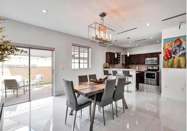 a view of a dining room with furniture a kitchen and chandelier