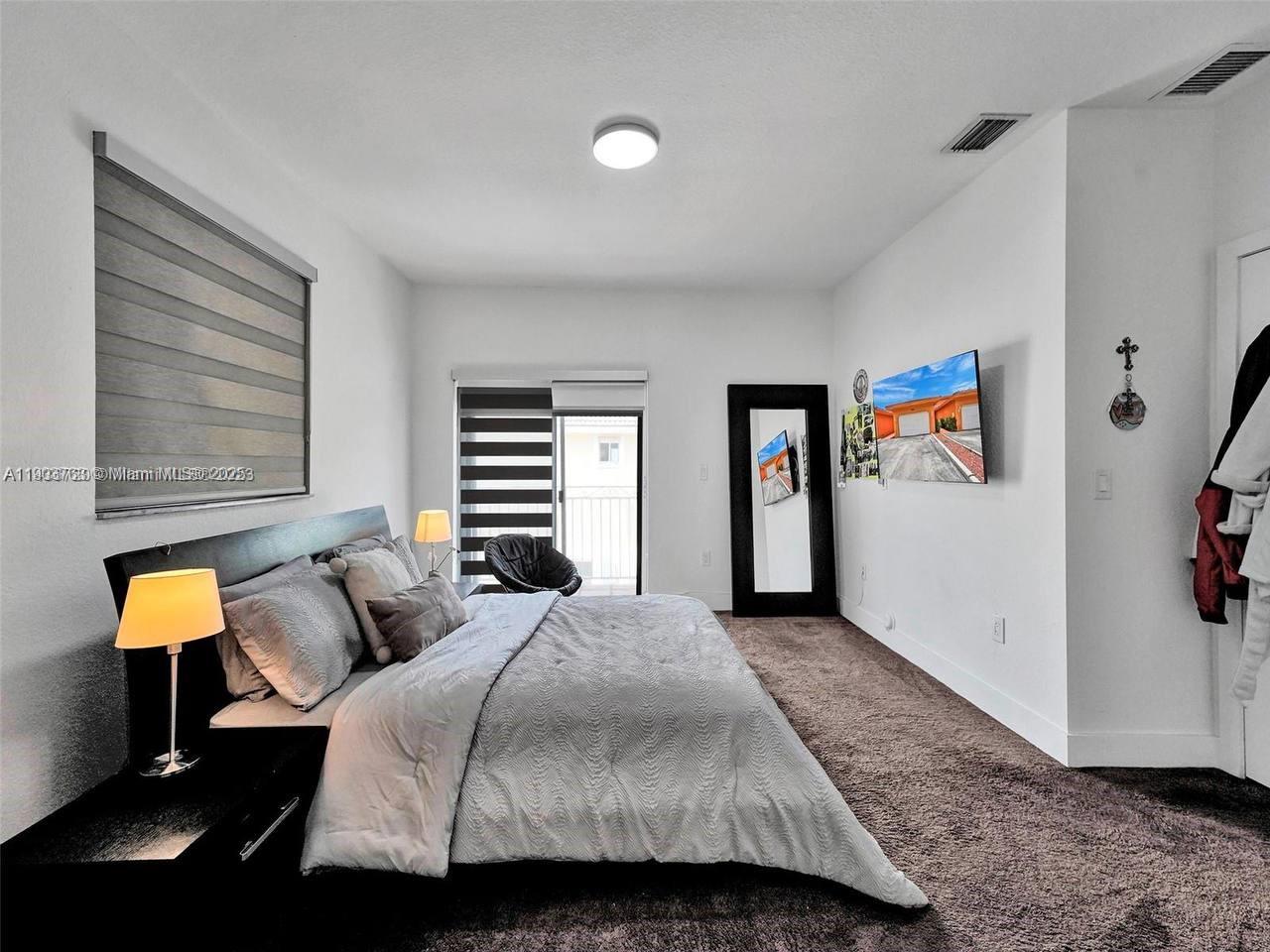 7565 Northwest 177th Terrace, Unit 7565 Hialeah, FL 33015 - Photo 29 of 35 a bedroom with a bed and a window