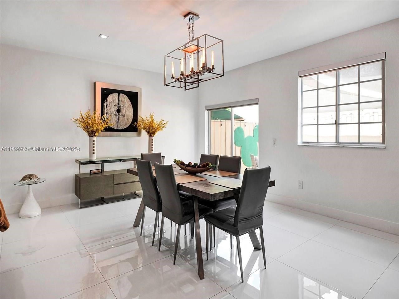 7565 Northwest 177th Terrace, Unit 7565 Hialeah, FL 33015 - Photo 30 of 35 a view of a dining room with furniture and a chandelier