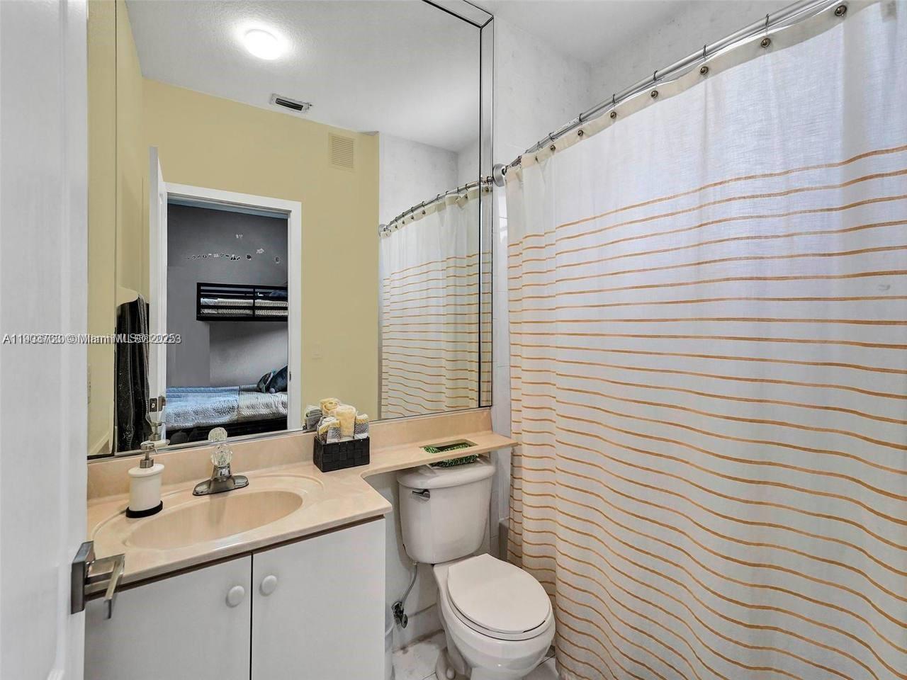 7565 Northwest 177th Terrace, Unit 7565 Hialeah, FL 33015 - Photo 35 of 35 a bathroom with a toilet a sink and mirror