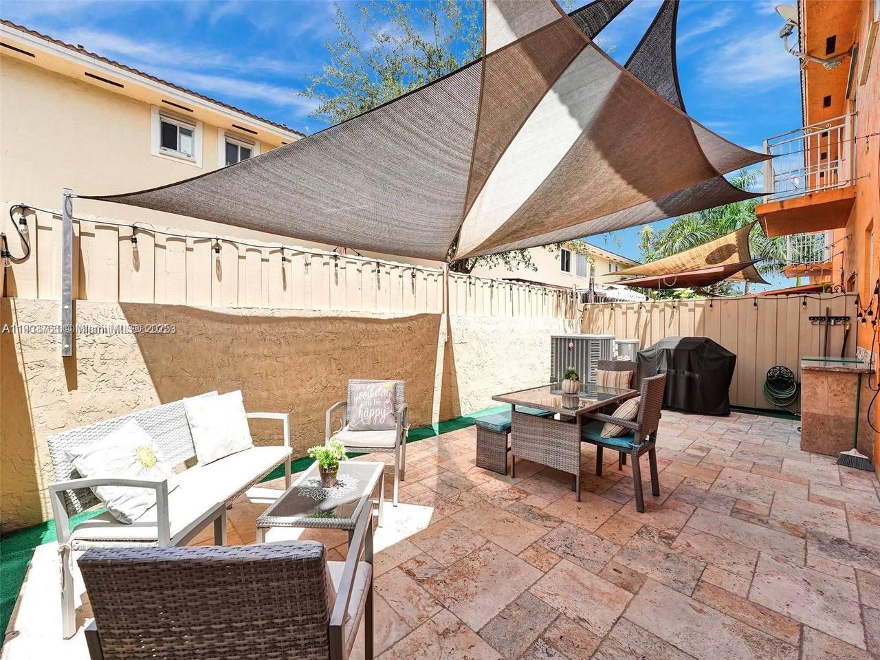7565 Northwest 177th Terrace, Unit 7565 Hialeah, FL 33015 - Photo 6 of 35 a outdoor space with the couches and dining table with the umbrella