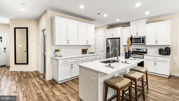 a kitchen with a refrigerator a stove top oven a sink dishwasher and white cabinets with wooden floor