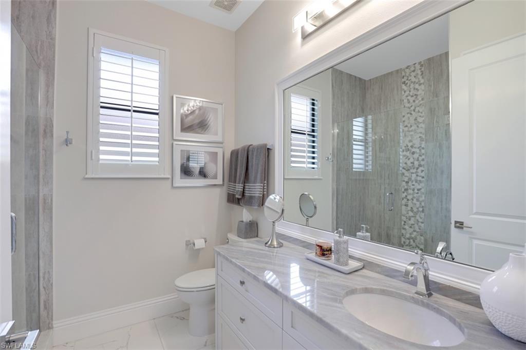 7323 Acorn Way Naples, FL 34119 - Photo 16 of 21 Bathroom featuring a tile shower, vanity, healthy amount of natural light, and light tile floors