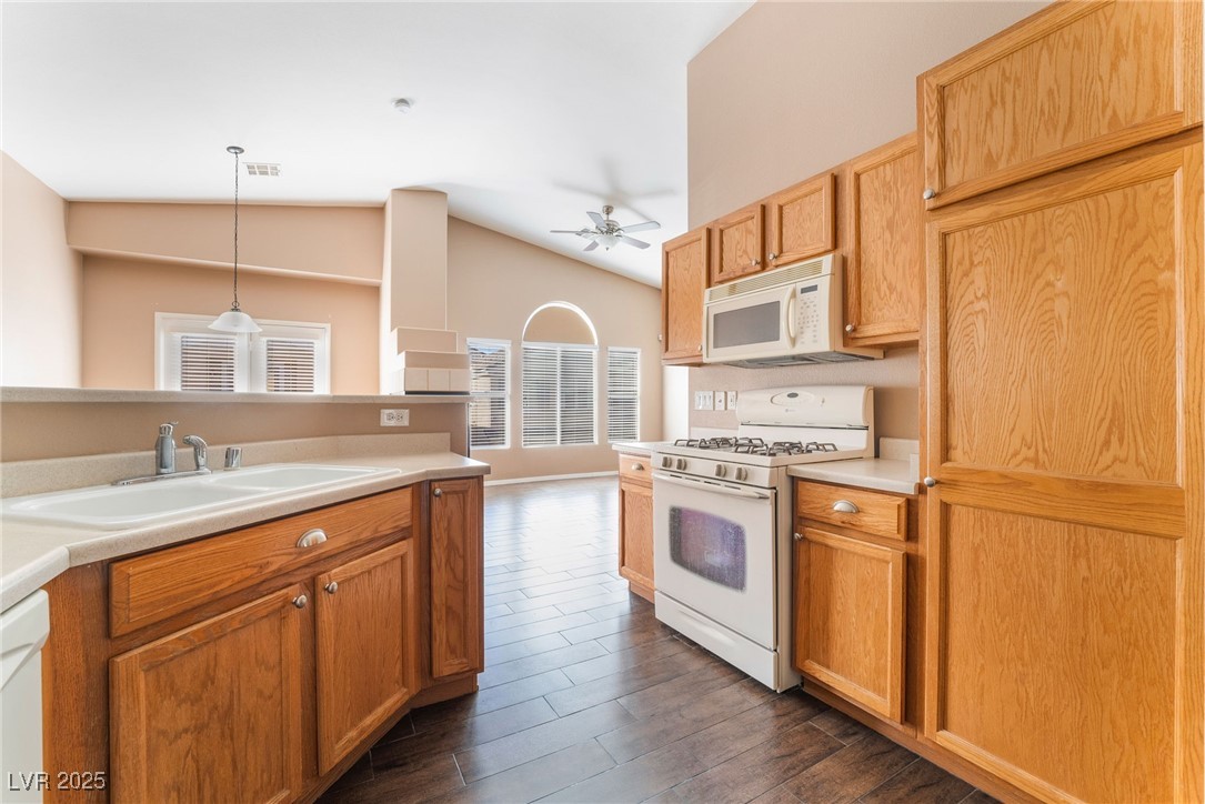 1570 Rusty Ridge Lane Henderson, NV 89002 - Photo 19 of 35 Kitchen with a sink, ceiling fan, white appliances, vaulted ceiling, and dark wood-type flooring