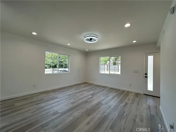 an empty room with wooden floor and windows