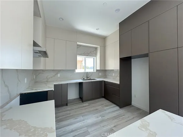 a large kitchen with a wooden floor and stainless steel appliances