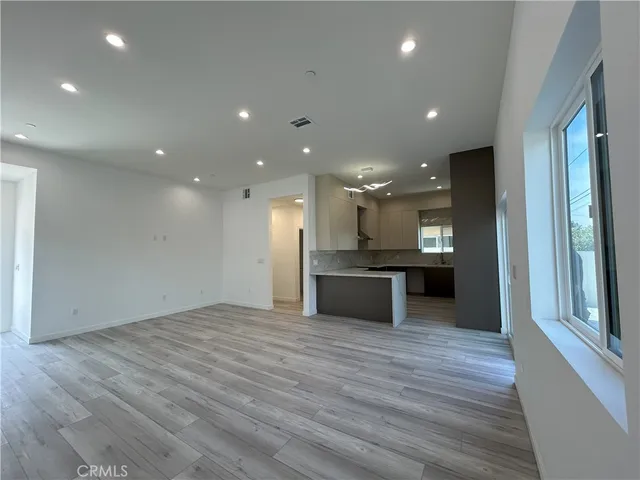 a view of kitchen with kitchen island wooden floor center island and stainless steel appliances