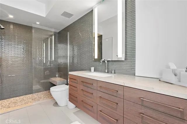 a spacious bathroom with a granite countertop sink toilet a mirror and shower