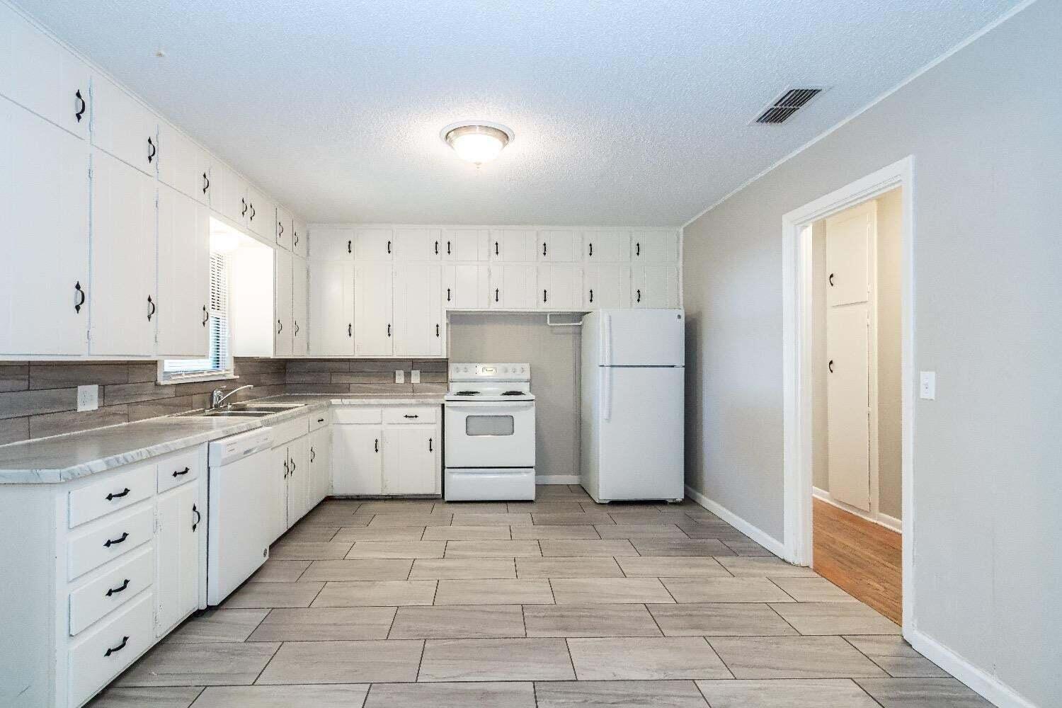 4212 42nd Street Lubbock, TX 79413 - Photo 7 of 18 a kitchen with white cabinets and white appliances