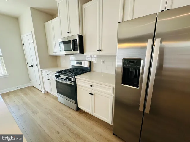 a kitchen with stainless steel appliances a refrigerator a stove a microwave and white cabinets