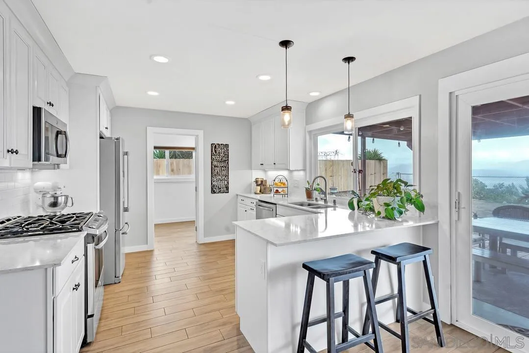 13415 Pequot Drive Poway, CA 92064 - Photo 14 of 63 a kitchen with kitchen island granite countertop a stove a refrigerator a oven a sink with island and chairs