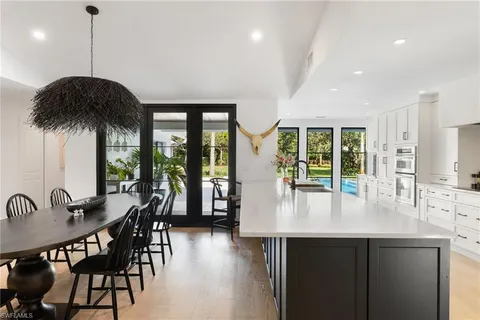 a kitchen with stainless steel appliances granite countertop a stove a refrigerator a dining table and chairs with wooden floor