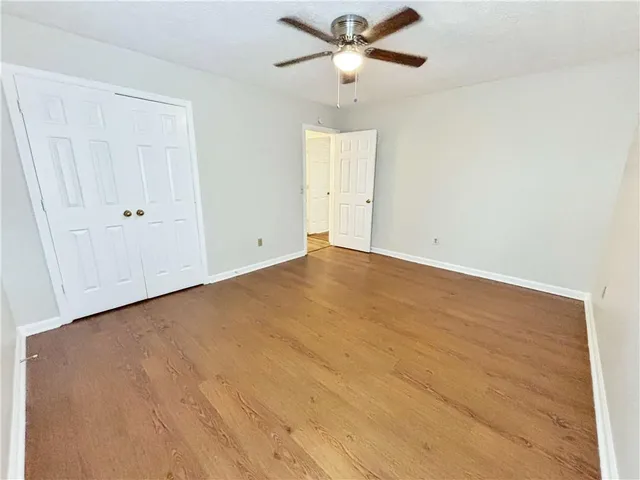 an empty room with a ceiling fan and wooden floor