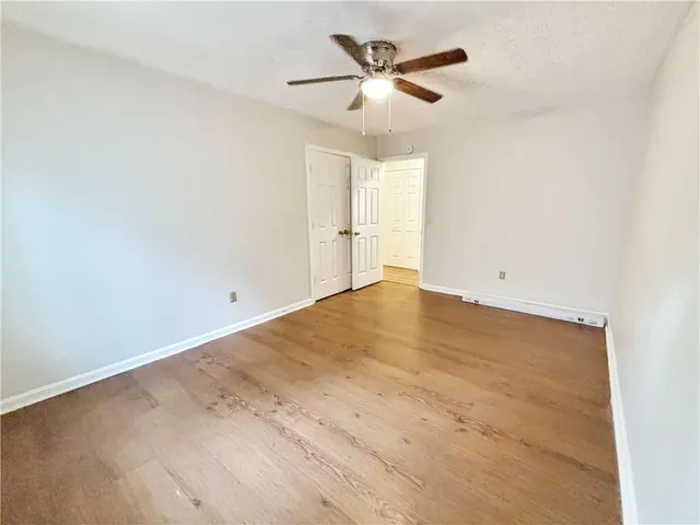en empty room with wooden floor and ceiling fan