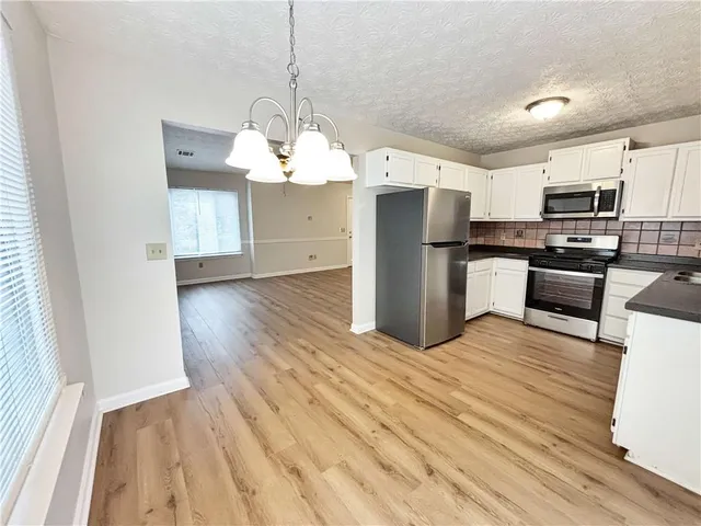 a open kitchen with stainless steel appliances granite countertop a refrigerator a stove oven a sink dishwasher and a refrigerator with wooden floor